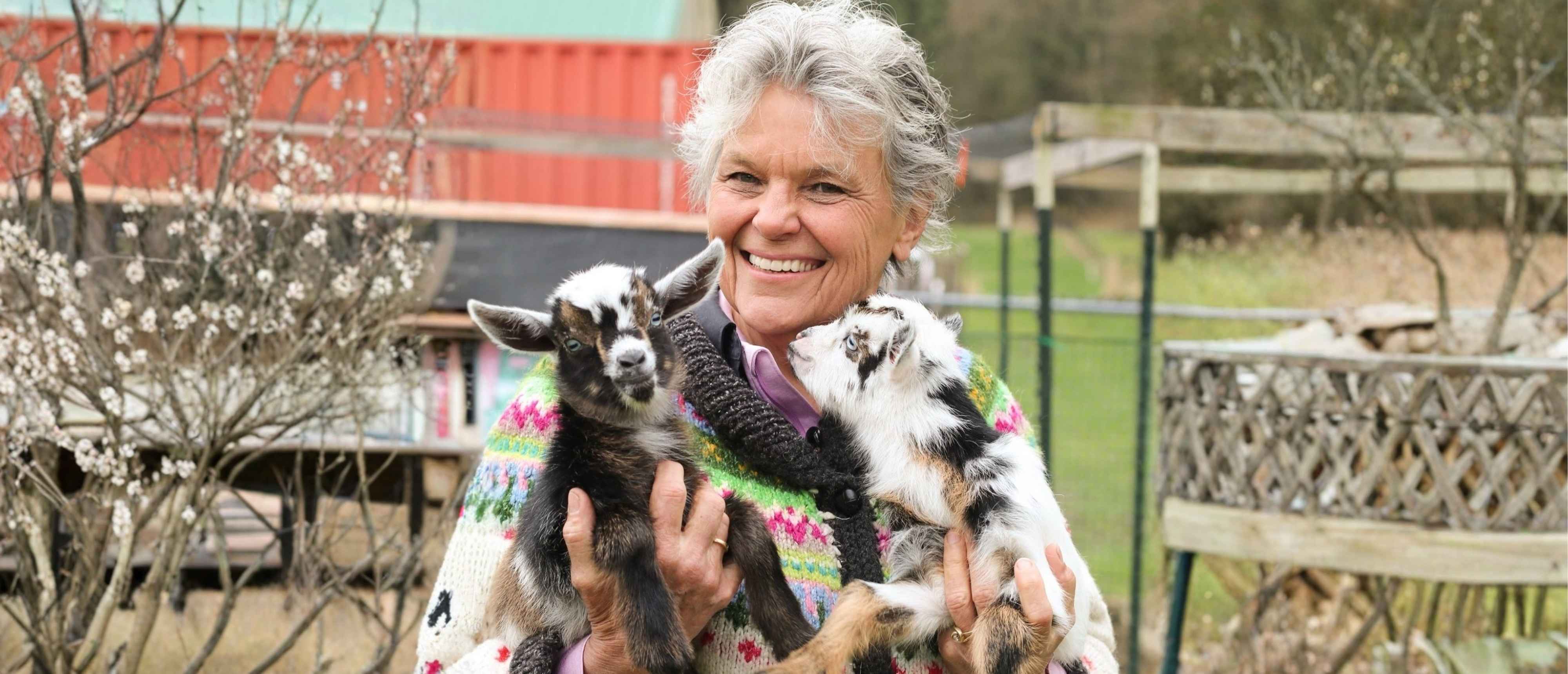 Grace smiling while holding baby goats at Grace Harbor Farm